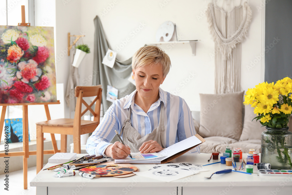 Mature female artist drawing sketch in  workshop