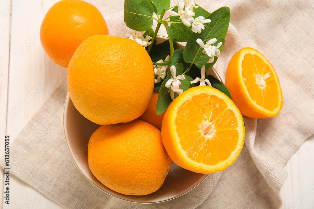 Bowl of oranges with blooming branch on white table