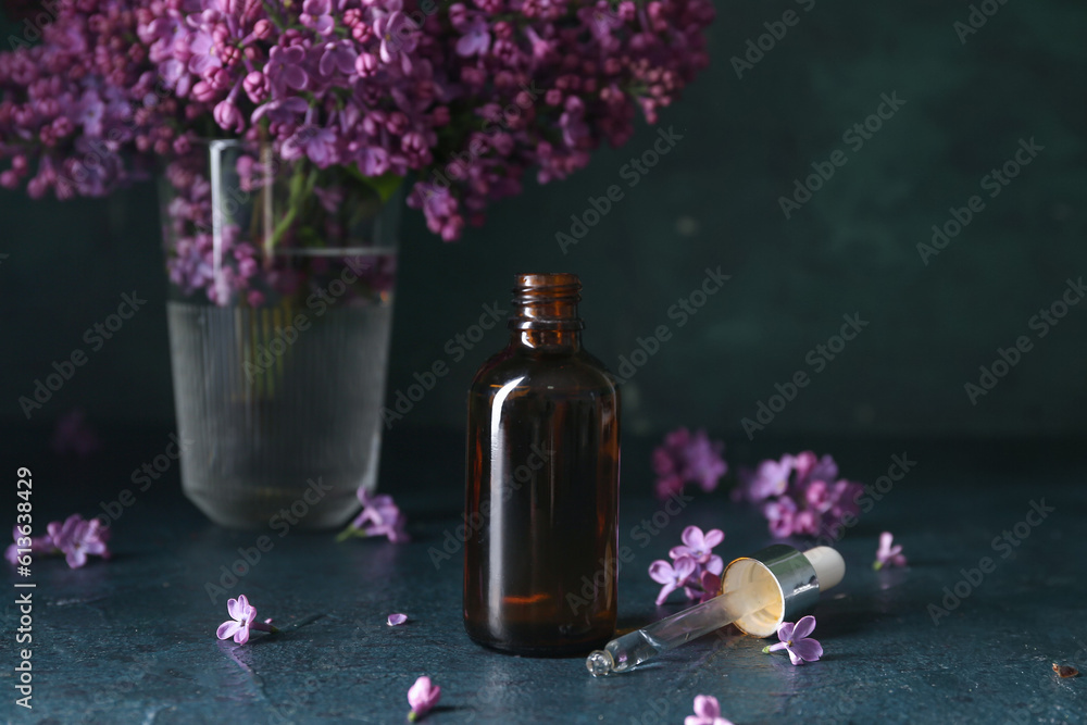 Bottle of cosmetic oil with beautiful lilac flowers on dark table