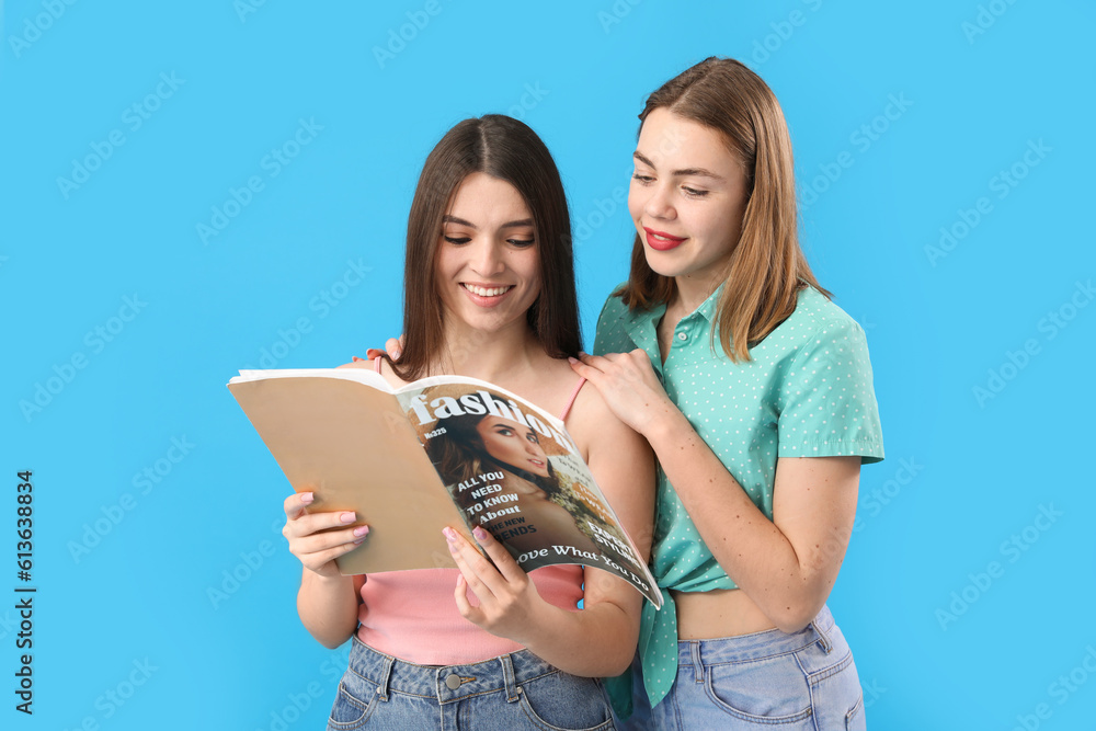 Female friends reading magazine on blue background