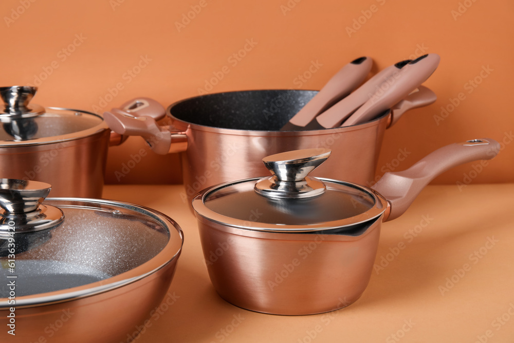 Set of copper kitchen pots and kitchen utensils on color background, closeup