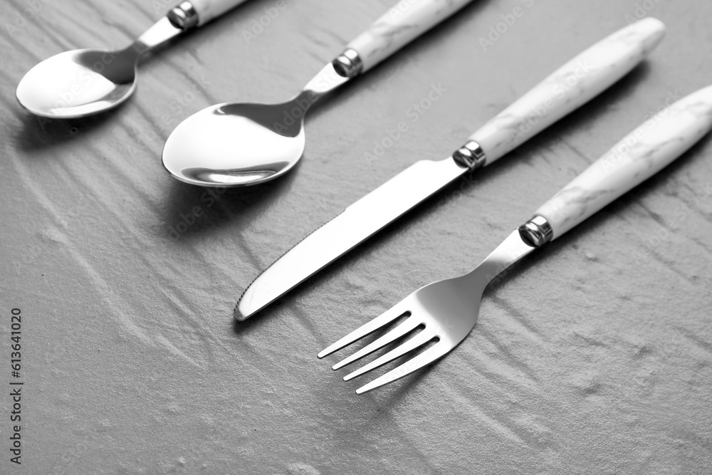 Stainless steel cutlery with plastic handles on grey background