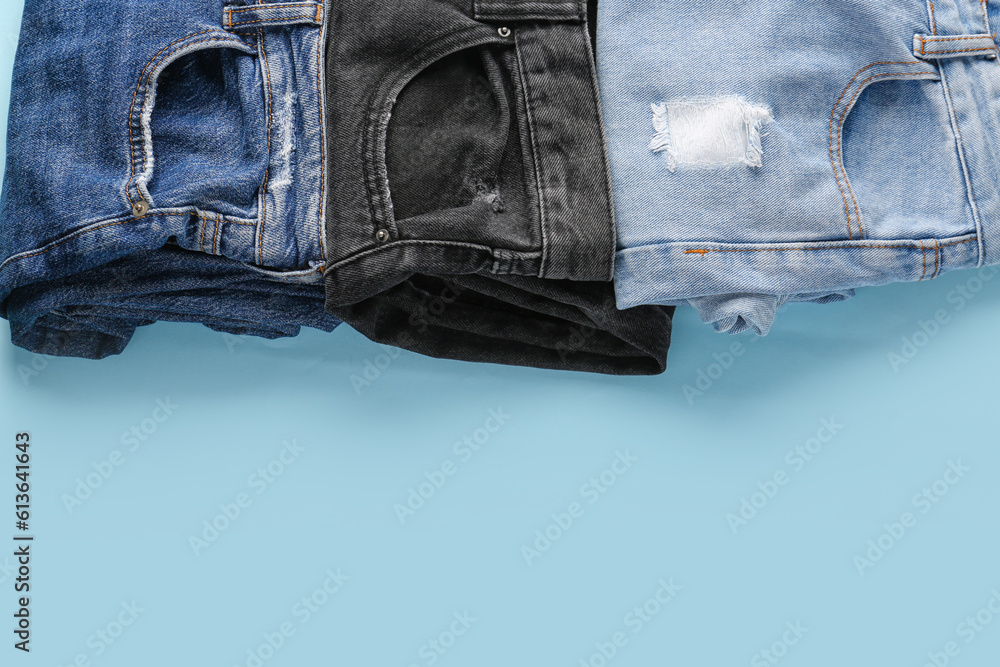 Different folded jeans on blue background