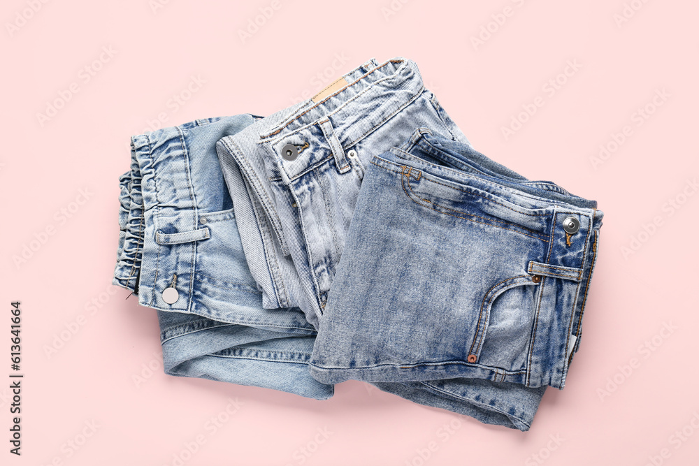 Different folded jeans on pink background