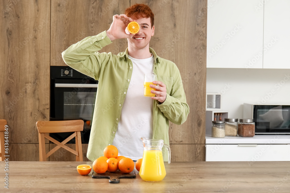 Young man with glass of orange juice in kitchen