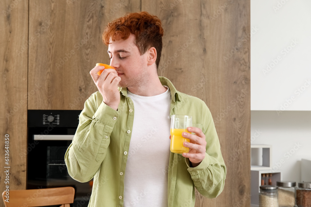 Young man with glass of orange juice in kitchen