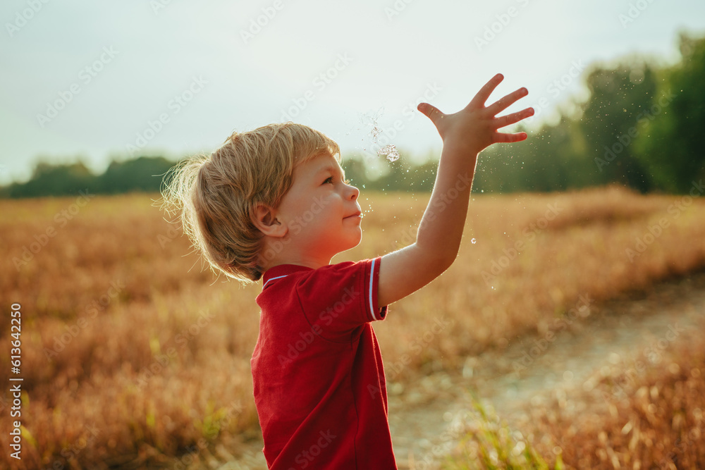 Little boy catches water droplets in the air