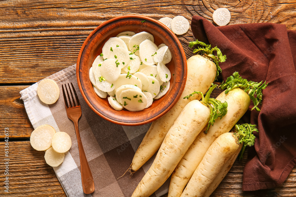 Bowl with slices of fresh daikon radish on wooden background