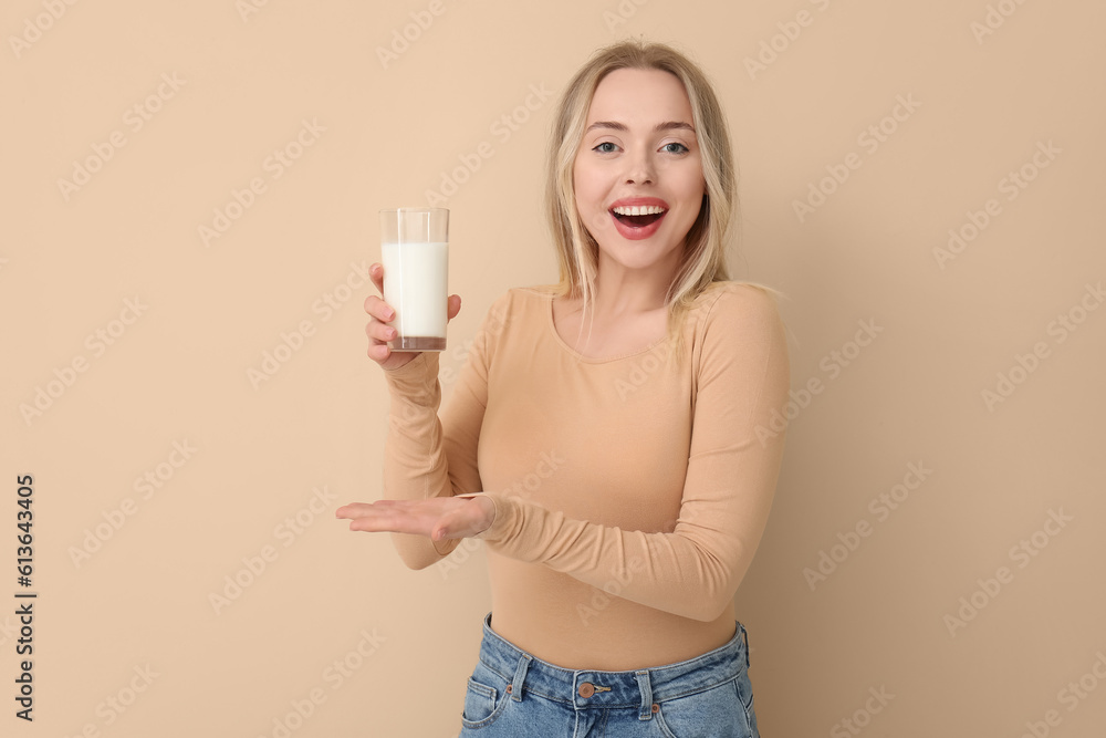 Young woman with glass of milk on beige background