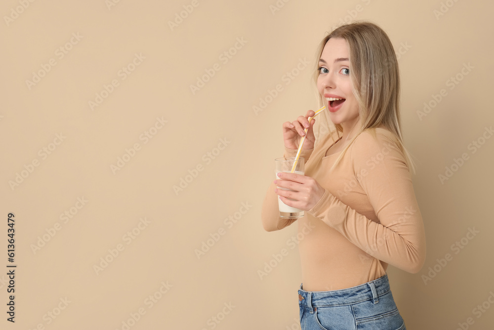 Young woman with glass of milk on beige background