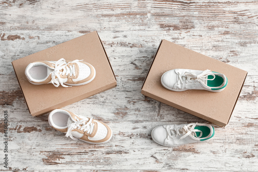 Cardboard boxes with stylish sneakers on light wooden background