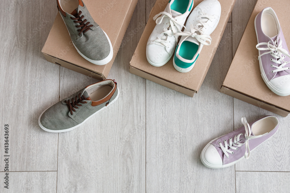 Cardboard boxes with different stylish sneakers on light wooden background