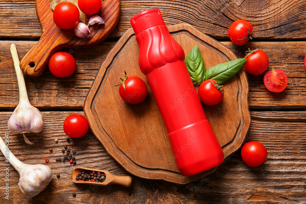 Board with bottle of ketchup and tomatoes on wooden background