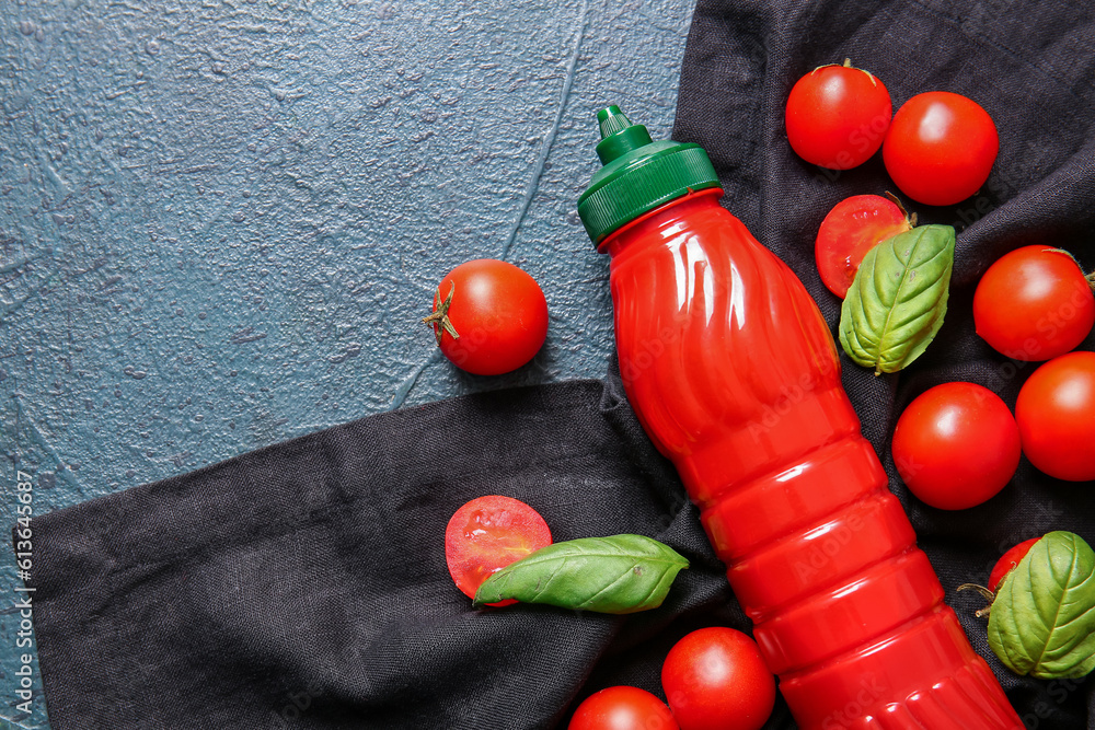 Bottle of ketchup and tomatoes on dark background