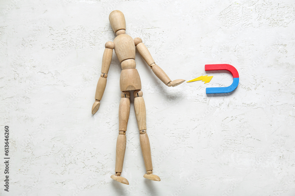 Wooden mannequin with magnet on white background