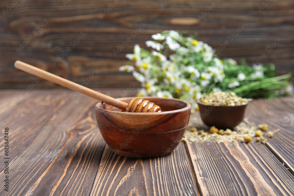 Bowl of honey, fresh and dried chamomile flowers on wooden background