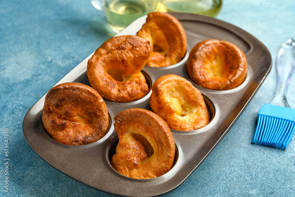 Baking tin with tasty Yorkshire pudding on blue background