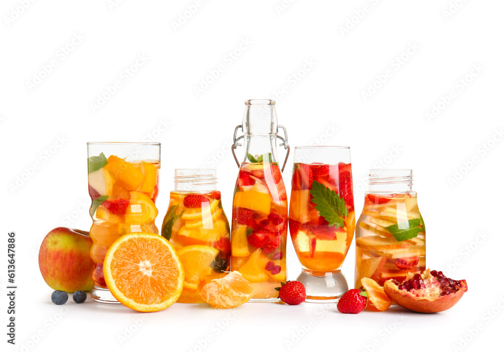 Glasses and bottles of infused water with different sliced fruits on white background