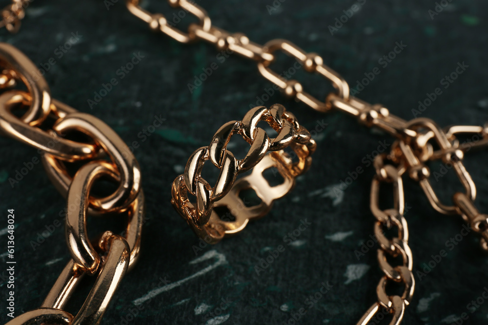 Beautiful chain bracelets and ring on black background