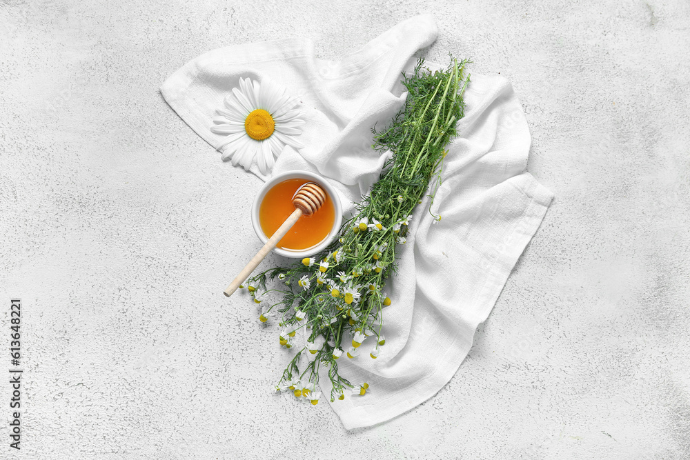 Composition with bowl of honey and fresh chamomile flowers on light background