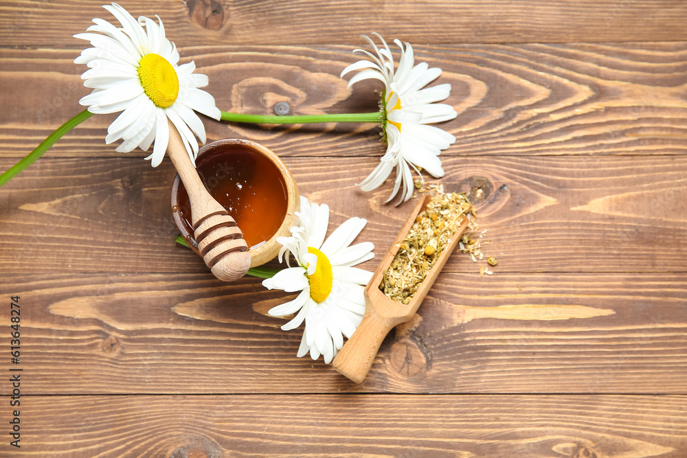 Bowl of honey, fresh and dried chamomile flowers on wooden background