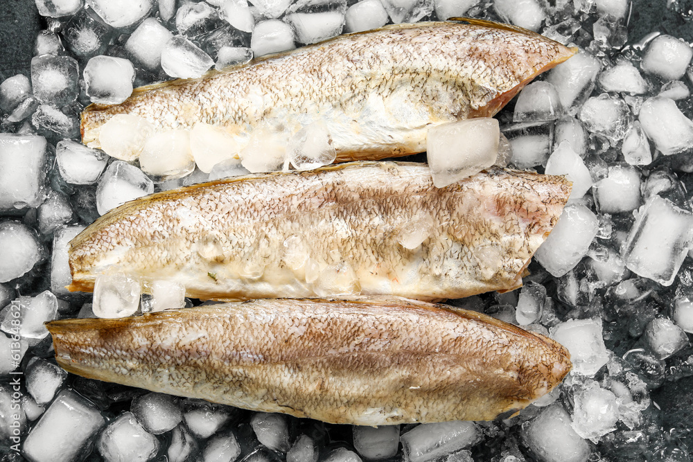 Raw codfish with ice cubes on dark background