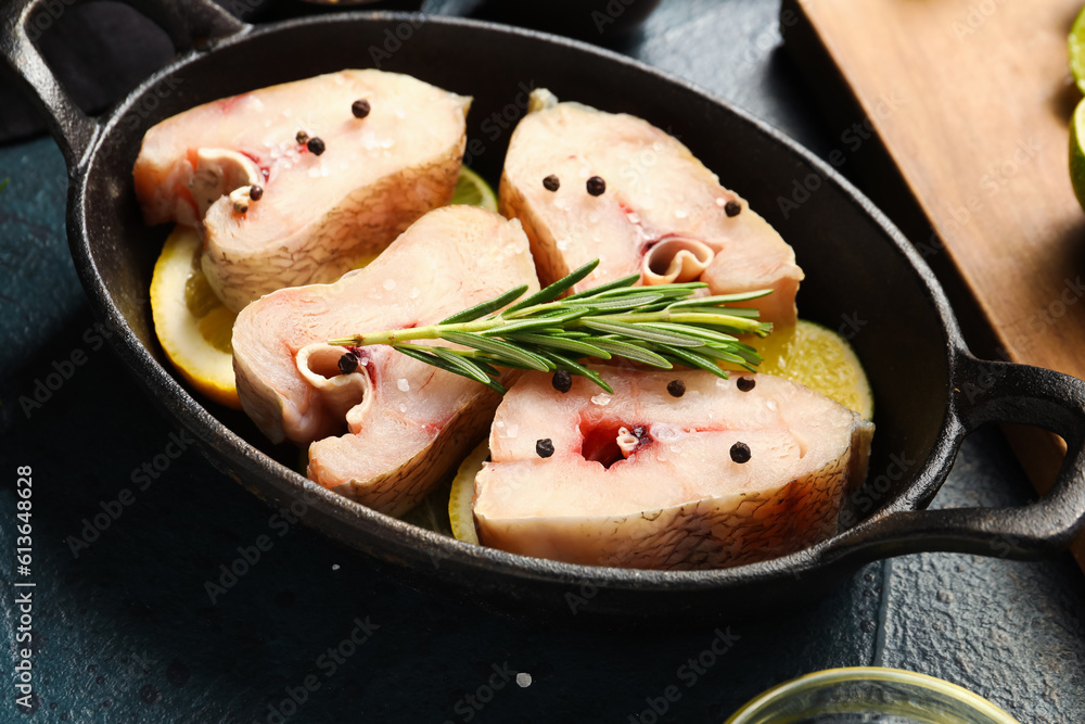 Baking dish with pieces of raw codfish on dark background