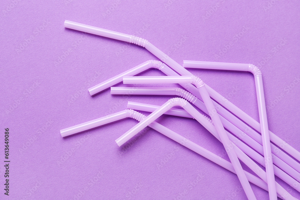 Lilac plastic straws on purple background