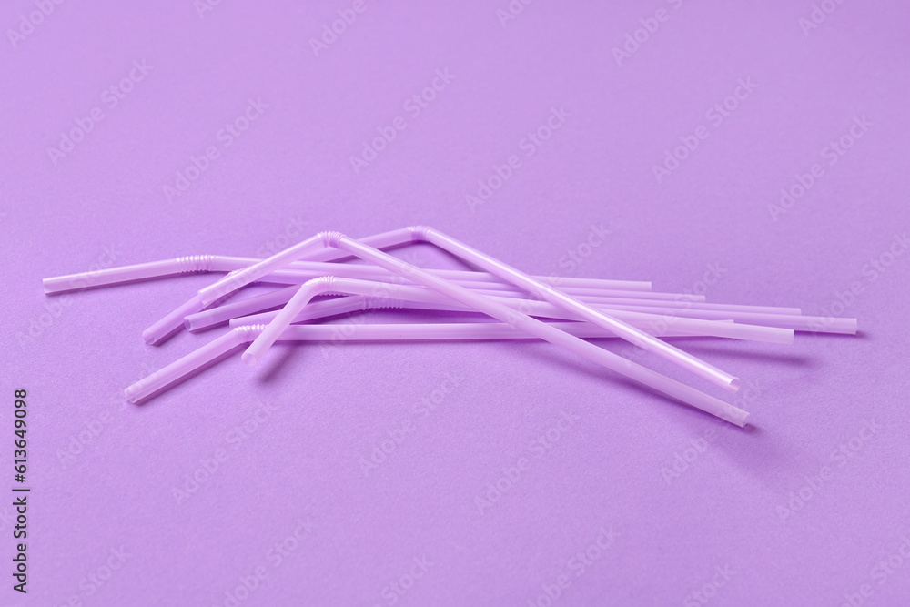 Lilac plastic straws on purple background