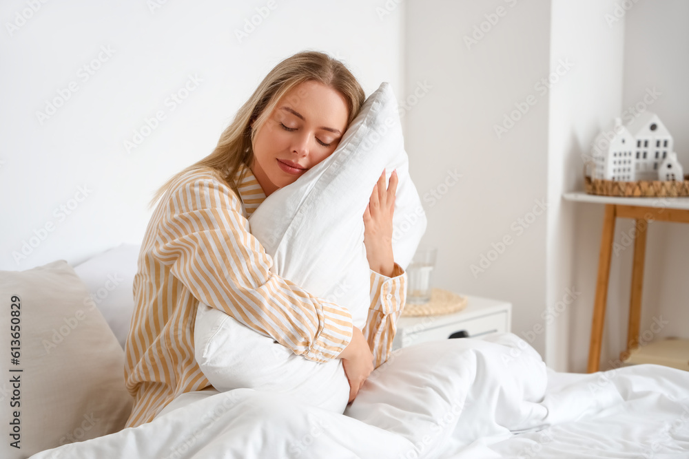 Young woman with pillow in bedroom