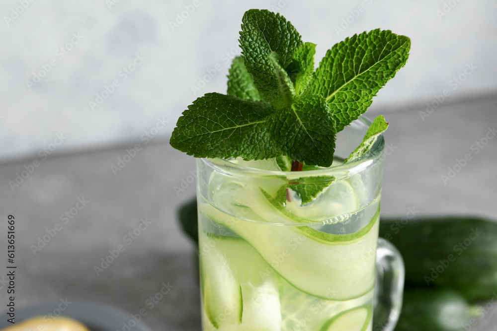 Glass of infused water with cucumber slices on grey table