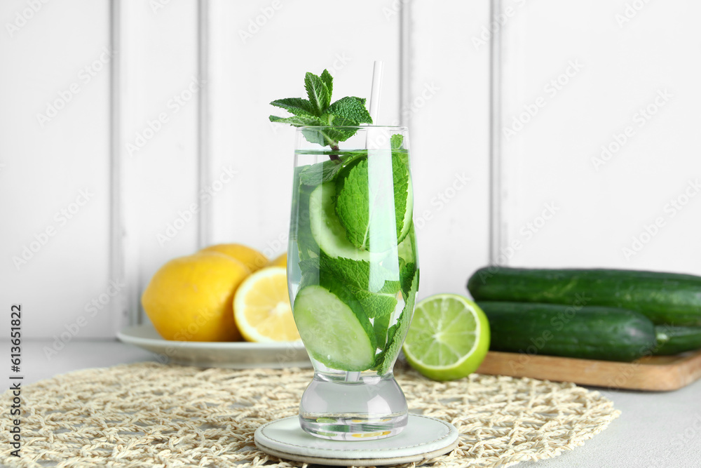 Glass of infused water with cucumber slices on blue background