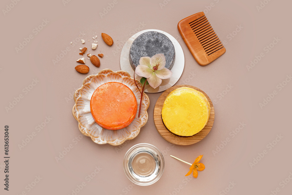 Solid shampoo bars with comb, flowers and almonds on beige background