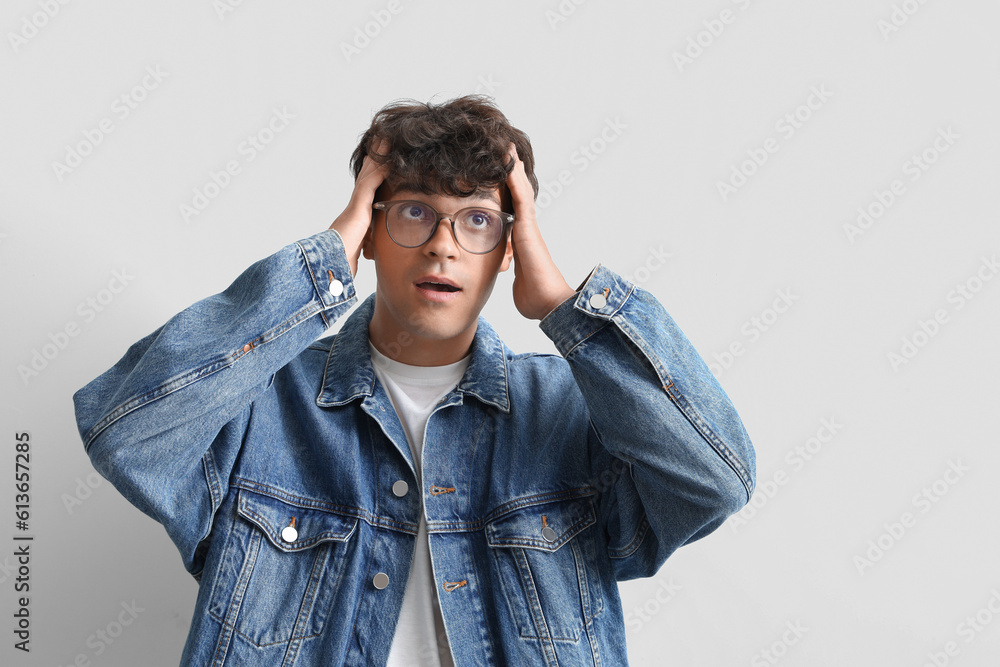 Surprised young man in stylish eyeglasses on light background