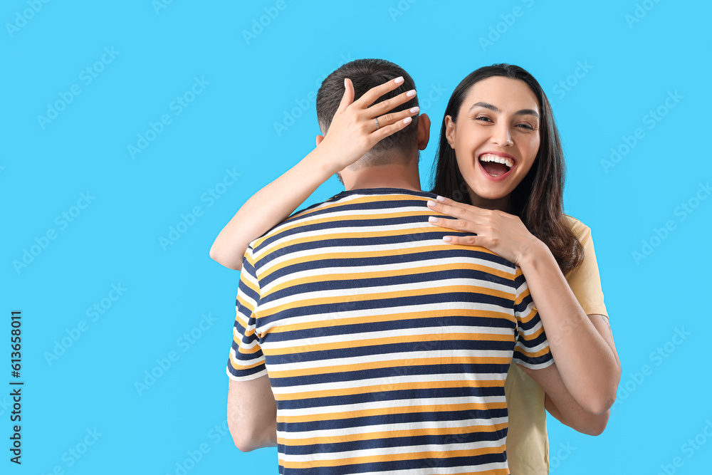 Happy engaged couple hugging on blue background