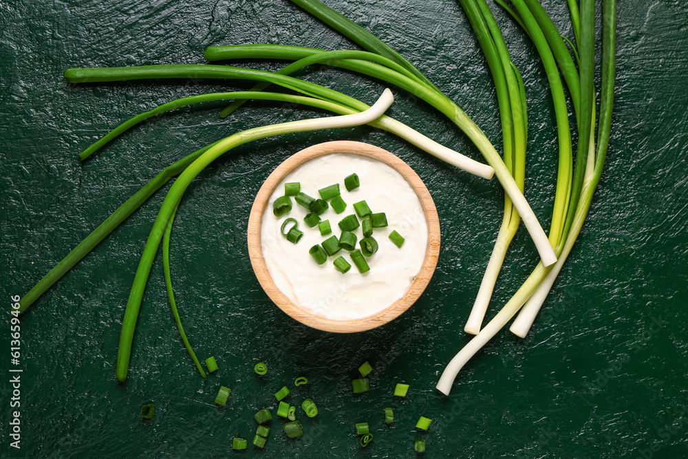 Bowl of tasty sour cream with sliced green onion on color background