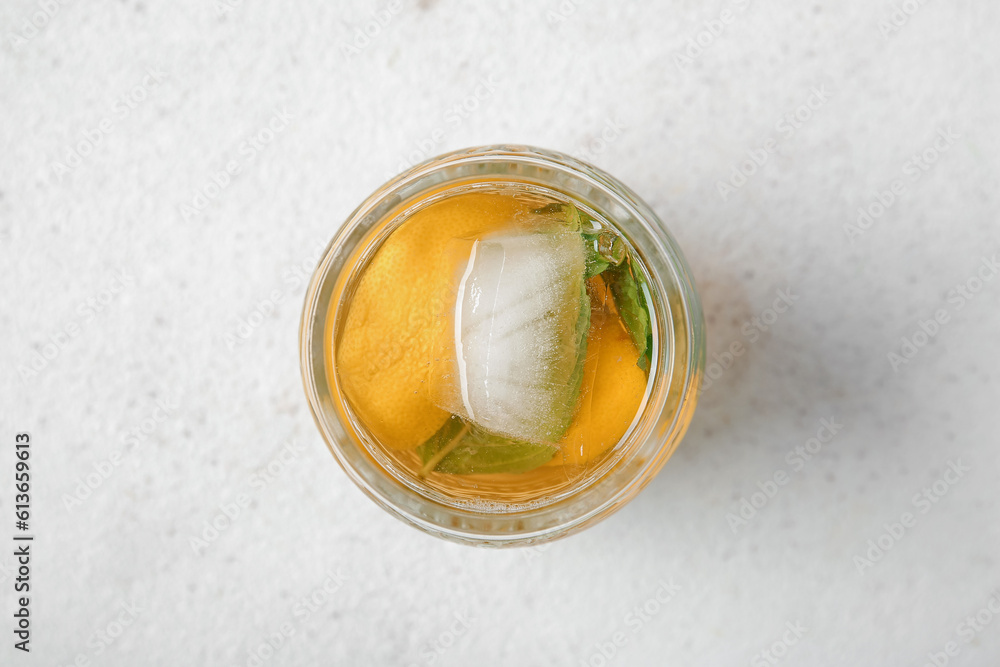 Glass of ice tea with lemon and mint on white background