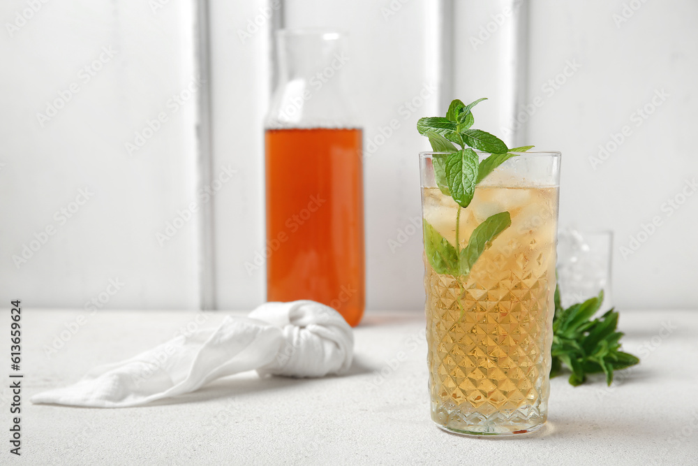 Glass and bottle of ice tea with mint on white background