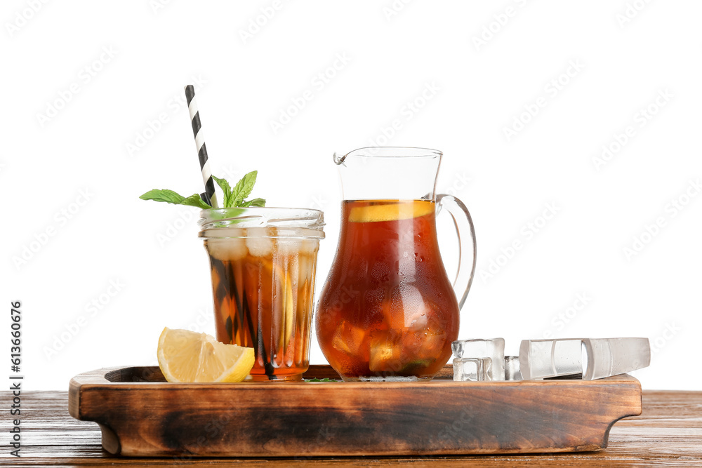 Jug and glass of ice tea with lemon on wooden table against white background