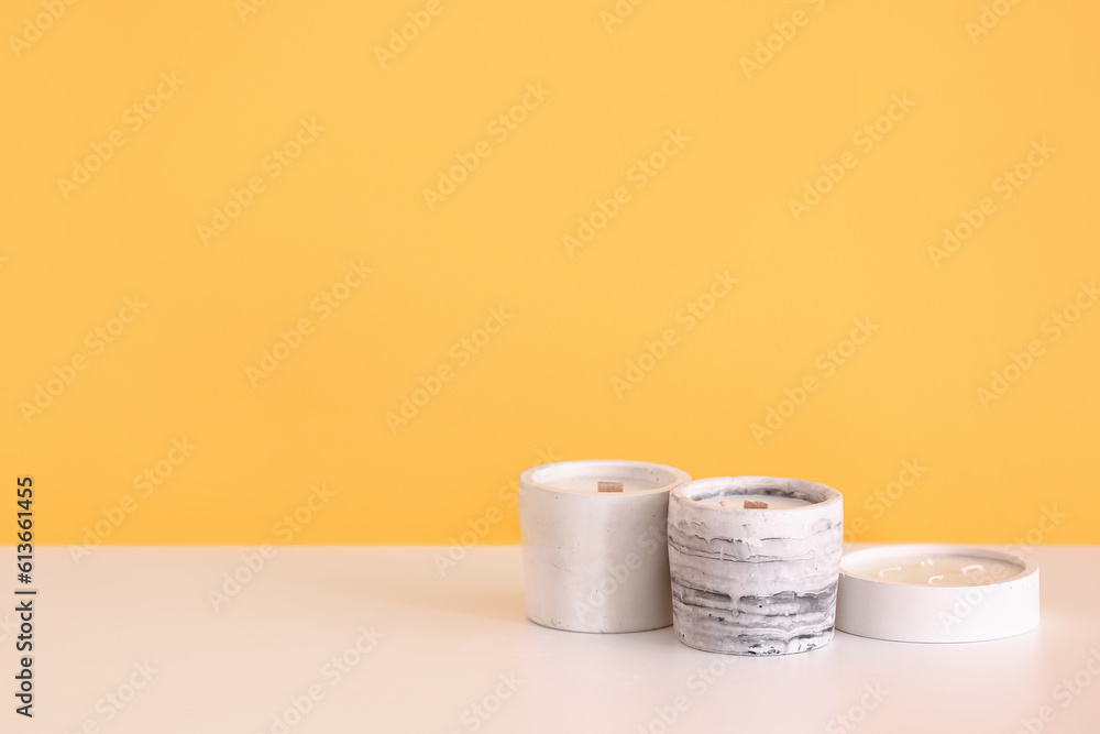 Holders with candles on table near orange wall in room