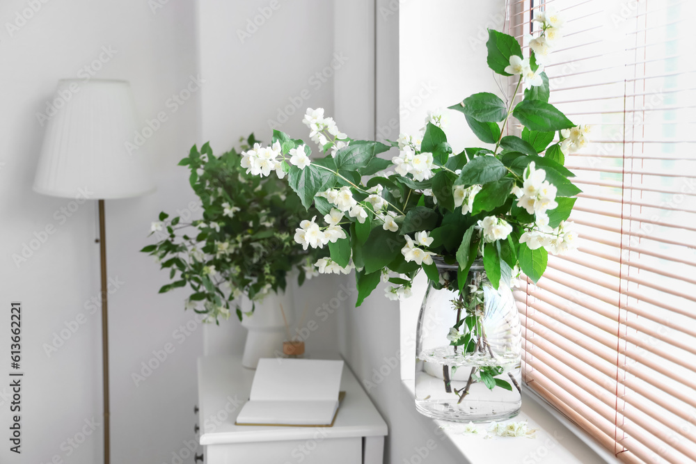 Vase with blooming jasmine flowers on windowsill, closeup