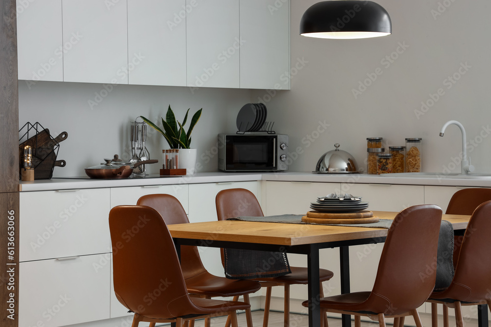 Interior of modern kitchen with dining table and glowing lamp