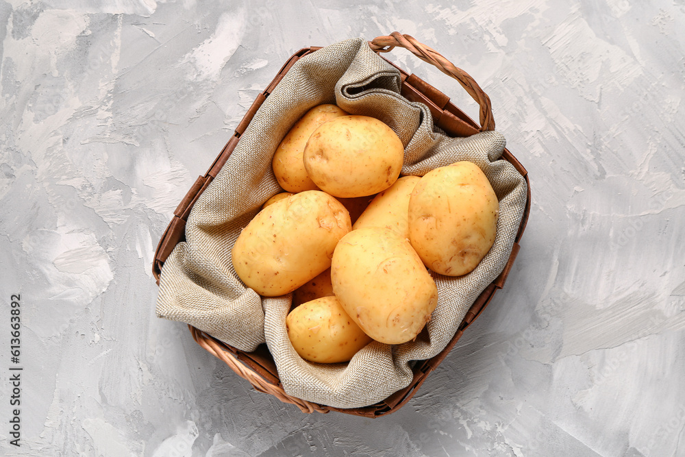 Wicker basket with raw baby potatoes on grey background