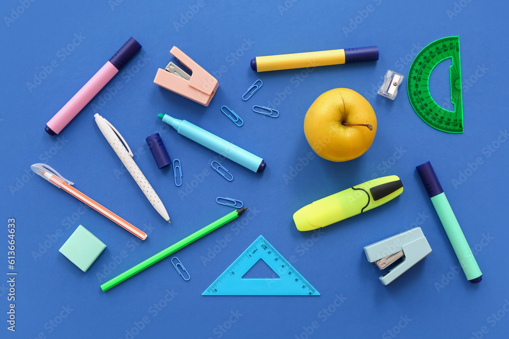 Fresh apple with different stationery on blue background