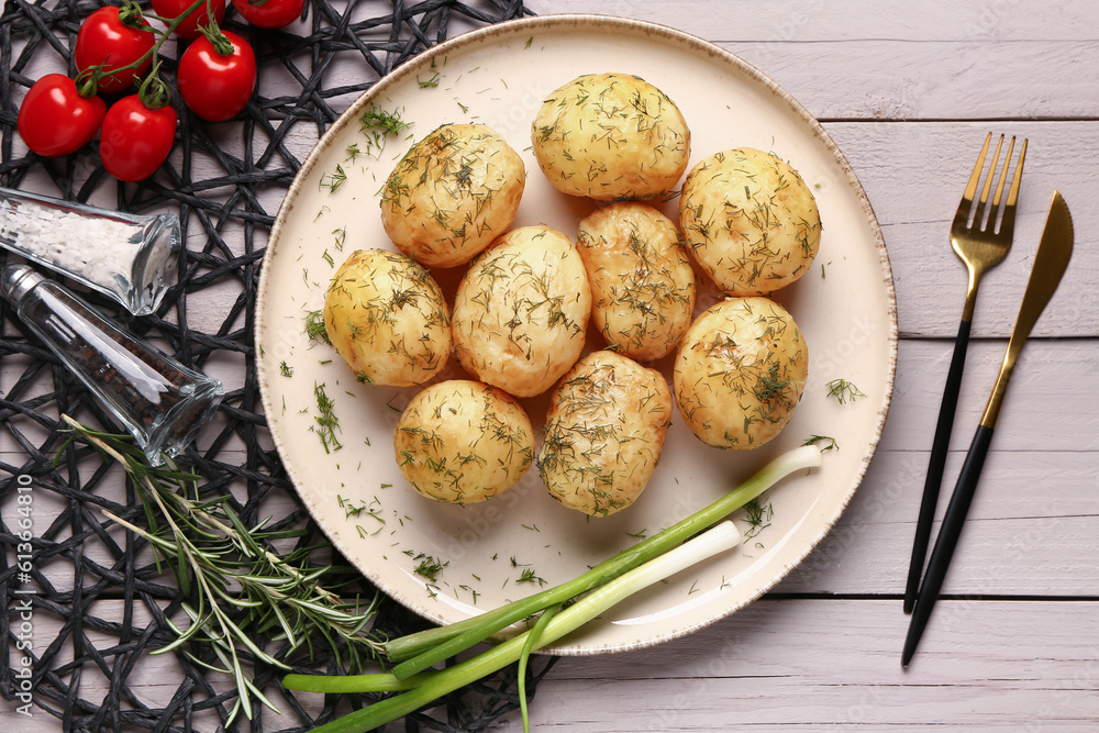 Plate of boiled baby potatoes with dill and tomatoes on grey wooden background