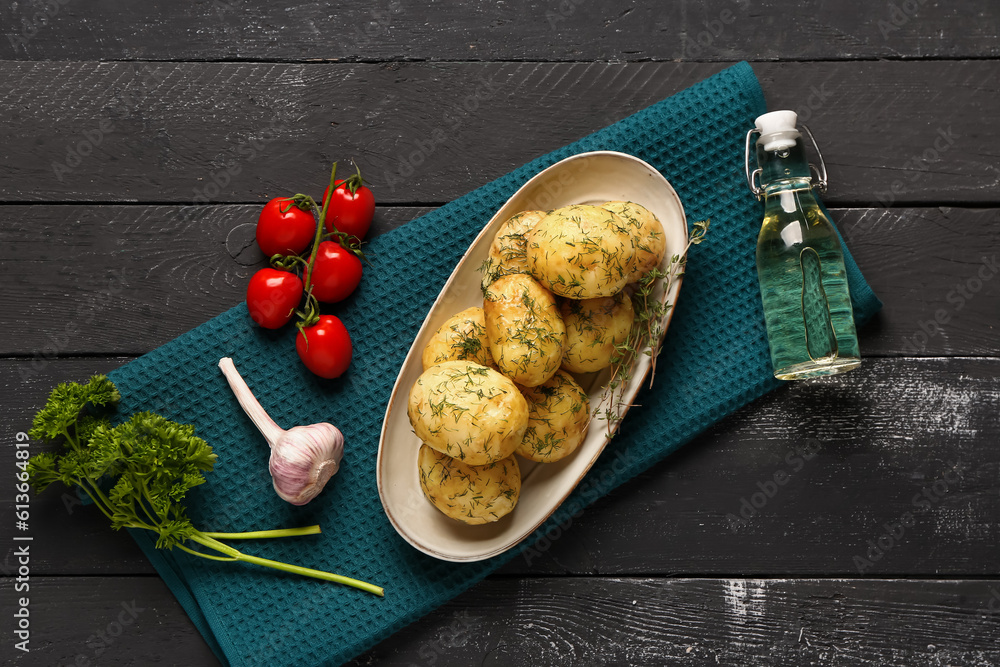 Plate of boiled baby potatoes with dill and tomatoes on black wooden background