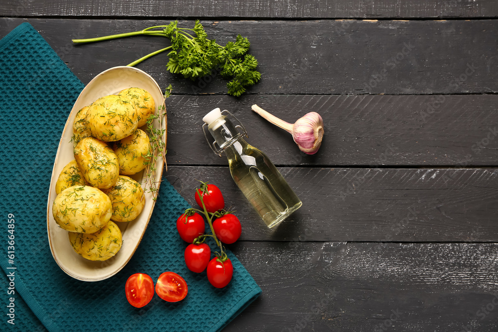 Plate of boiled baby potatoes with dill and tomatoes on black wooden background