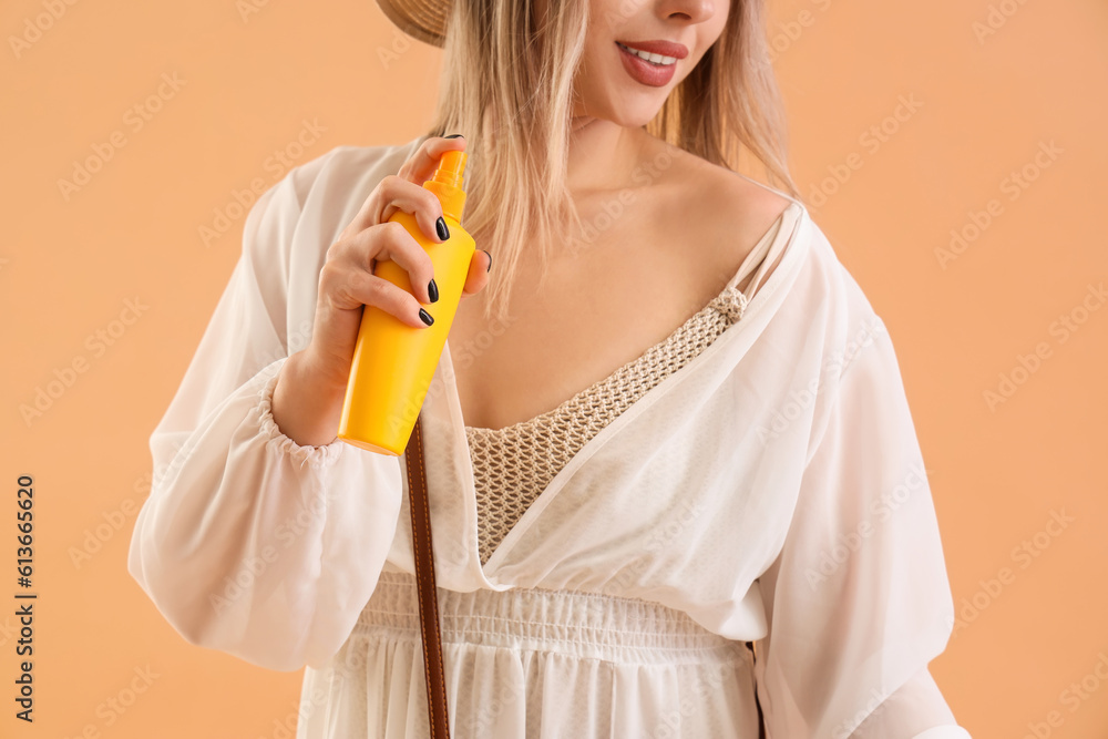 Young woman with sunscreen cream on beige background, closeup