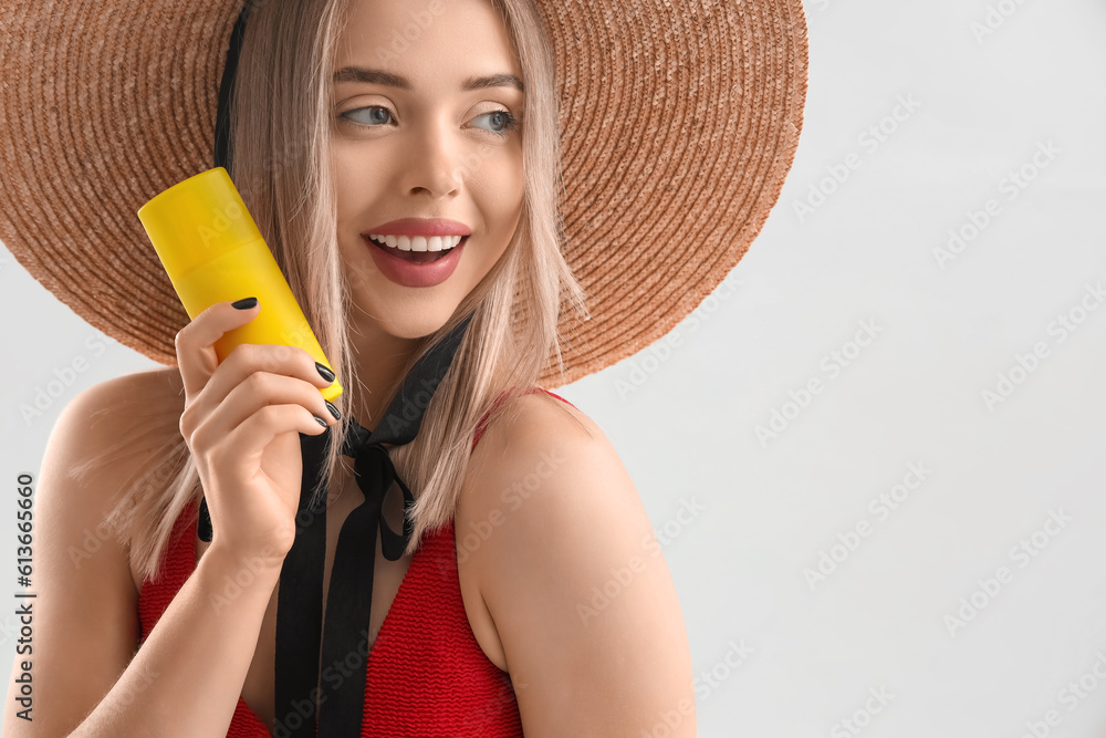 Young woman with sunscreen cream on light background, closeup