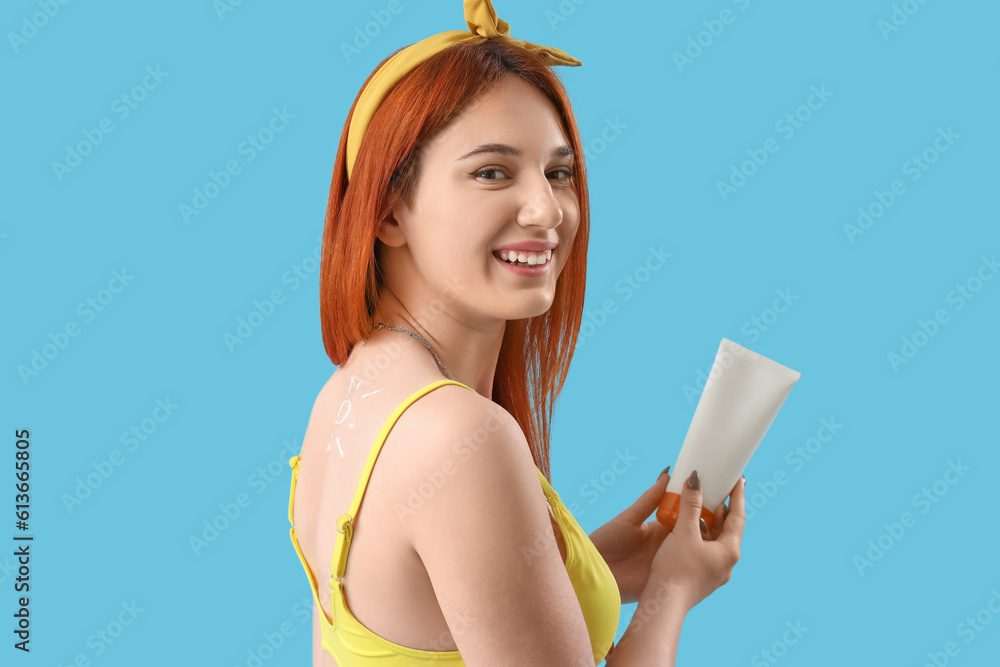 Young woman with sun made of sunscreen cream on blue background